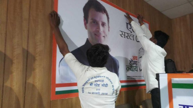 Worker putting up Rahul Gandhi’s posters while wearing a Modi T-shirt removed from Congress office