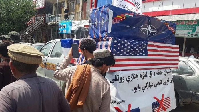 Taliban holds mock funeral with coffins wrapped in US and NATO flags after end of Afghanistan War