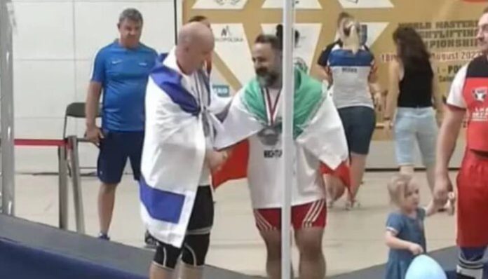 The Iranian weightlifter (R) shakes hands with the Israeli competitor (L).