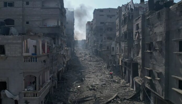 Rubble litters a street between smoldering buildings struck by an Israeli air raid in Gaza.